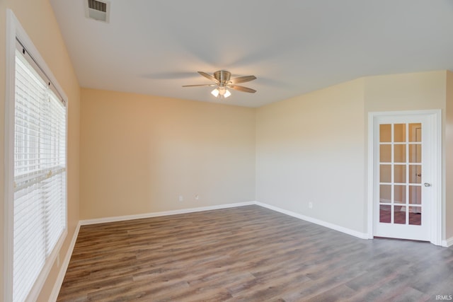 spare room featuring ceiling fan, visible vents, baseboards, and dark wood-style floors