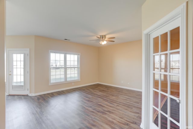 unfurnished room with visible vents, plenty of natural light, baseboards, and dark wood-style flooring