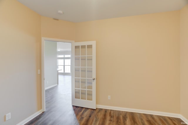 spare room featuring dark wood-style floors and baseboards