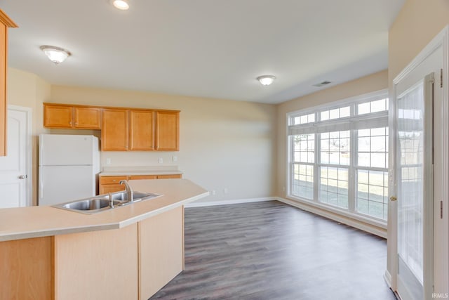 kitchen featuring visible vents, a sink, freestanding refrigerator, light countertops, and baseboards