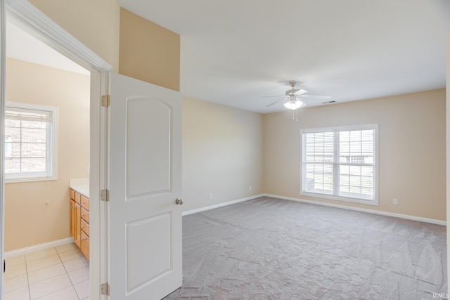 spare room with ceiling fan, a healthy amount of sunlight, light colored carpet, and baseboards