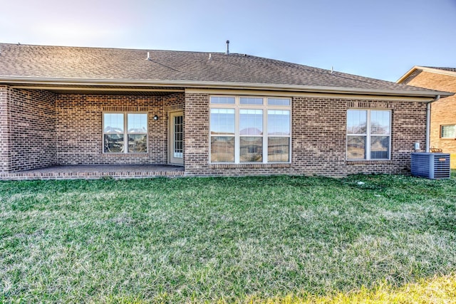 back of property featuring brick siding, cooling unit, a shingled roof, and a yard