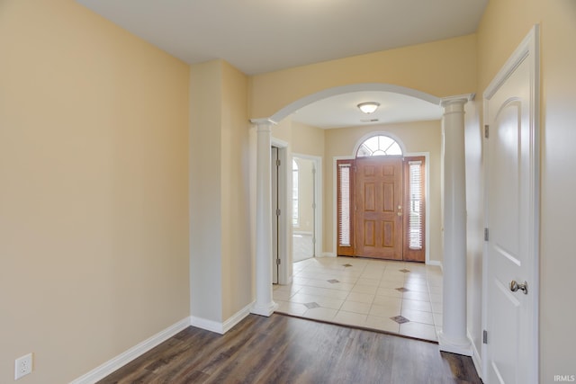 foyer featuring arched walkways, ornate columns, and wood finished floors