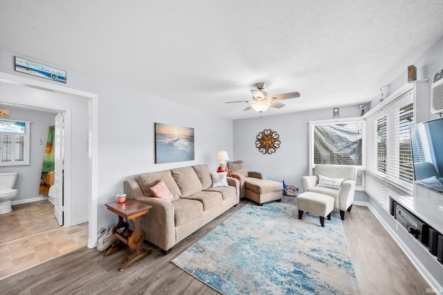 living room with a wealth of natural light, a textured ceiling, ceiling fan, and wood finished floors