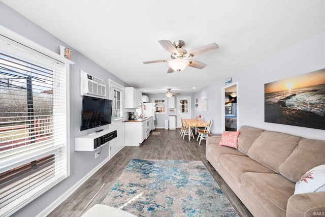 living area featuring an AC wall unit, dark wood finished floors, and a ceiling fan