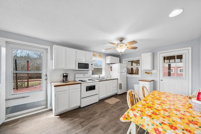 kitchen with white appliances, a healthy amount of sunlight, dark wood finished floors, and white cabinetry