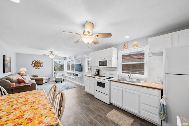 kitchen with dark wood finished floors, plenty of natural light, white cabinets, white appliances, and a sink