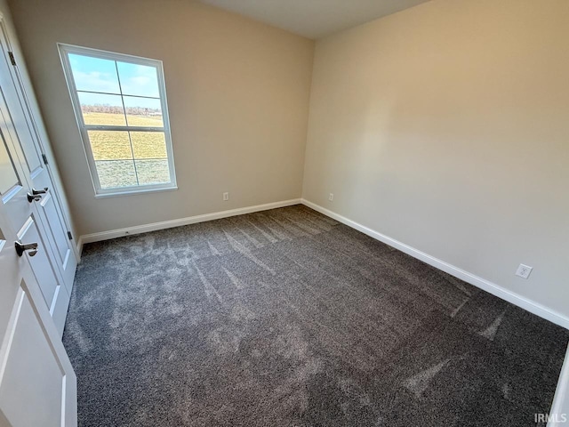 unfurnished room featuring baseboards and dark colored carpet