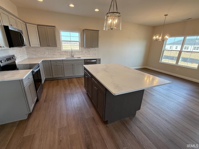 kitchen with a sink, stainless steel appliances, a notable chandelier, and gray cabinets