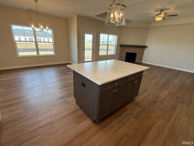 kitchen featuring dark wood finished floors, open floor plan, a fireplace, and baseboards