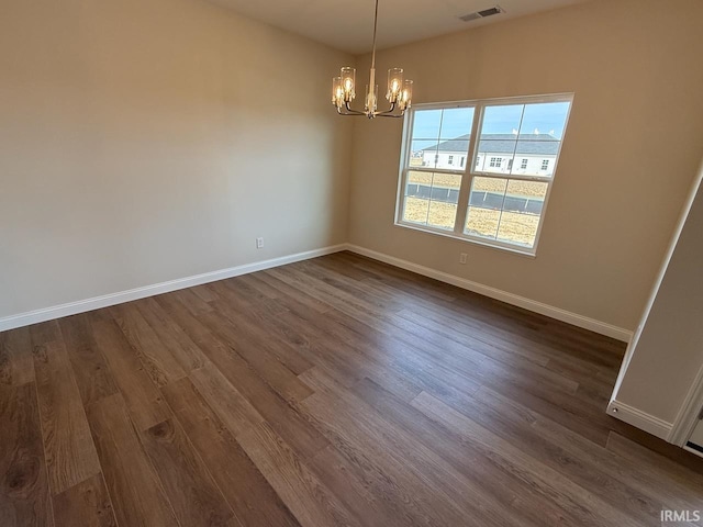 empty room featuring visible vents, baseboards, a notable chandelier, and dark wood-style floors