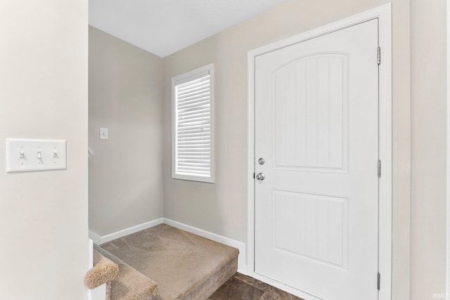 interior space with stairs, baseboards, and dark colored carpet