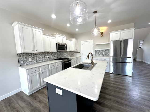 kitchen featuring tasteful backsplash, a center island with sink, dark wood-style floors, stainless steel appliances, and a sink