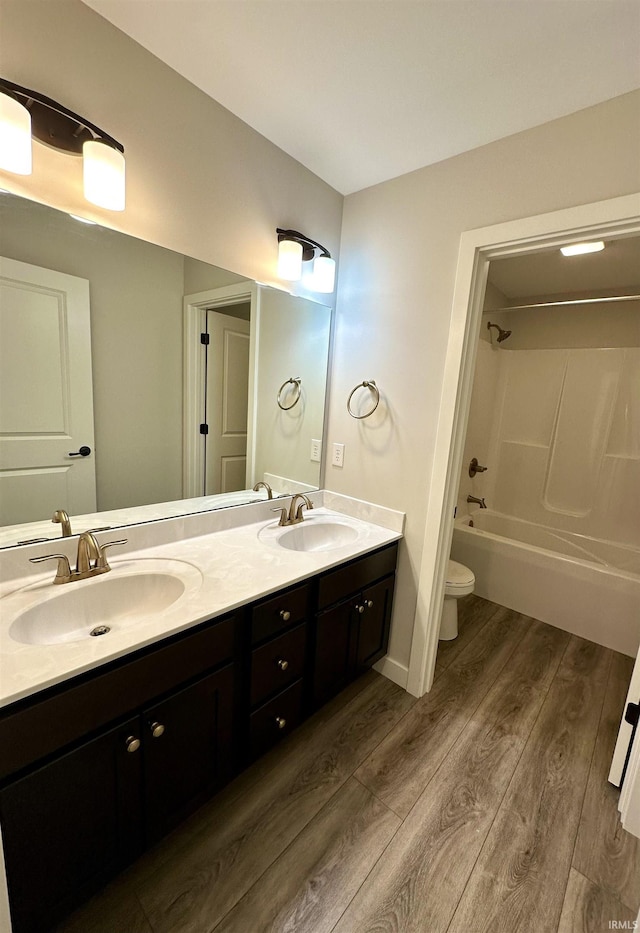 bathroom featuring double vanity, toilet, wood finished floors, and a sink