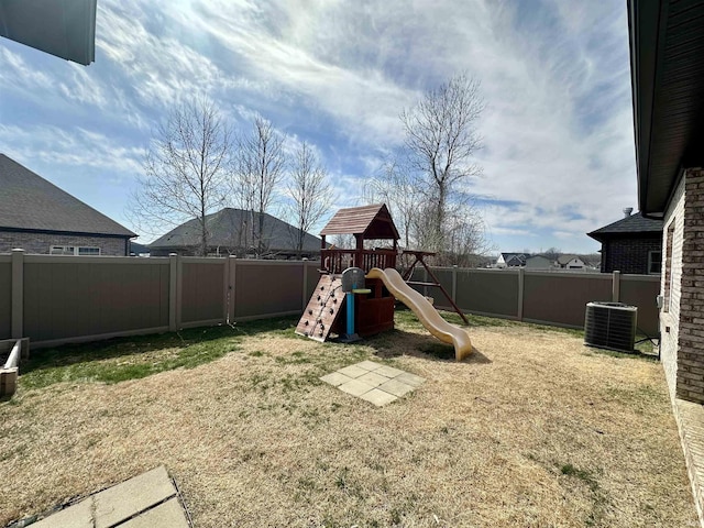 view of playground featuring a lawn, central AC, and a fenced backyard