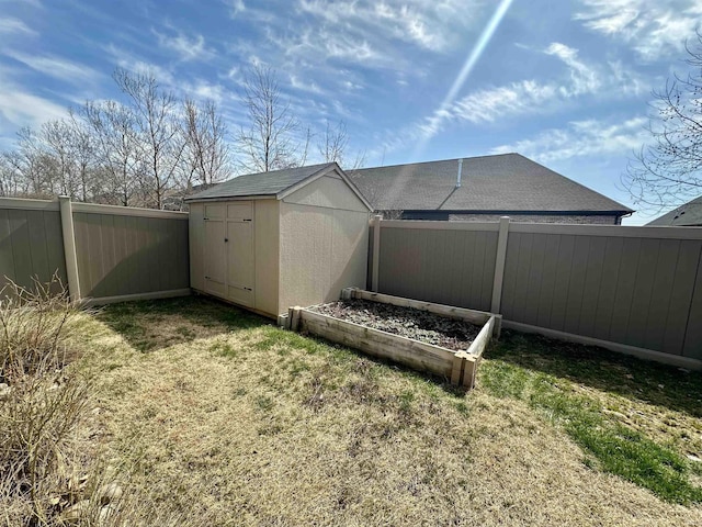 view of yard with a garden, a storage shed, a fenced backyard, and an outdoor structure