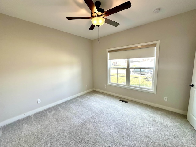 carpeted spare room featuring visible vents, ceiling fan, and baseboards