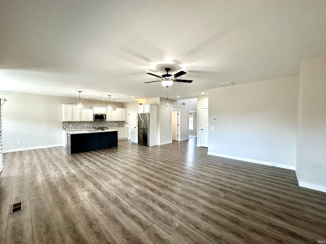 unfurnished living room featuring dark wood finished floors, visible vents, baseboards, and ceiling fan