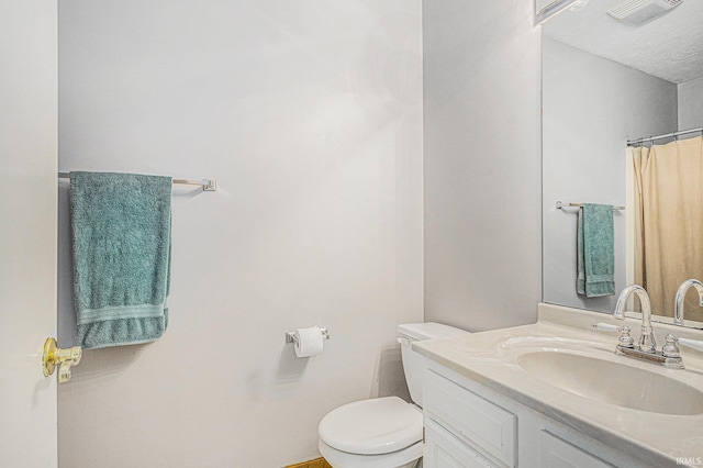 bathroom featuring vanity, toilet, and visible vents