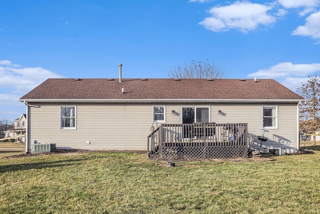 rear view of house featuring a wooden deck, fence, a yard, and roof with shingles