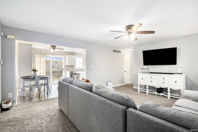 living room with visible vents, carpet flooring, baseboards, and ceiling fan