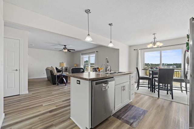 kitchen with white cabinetry, a sink, stainless steel dishwasher, dark countertops, and light wood-type flooring