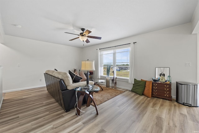 living area featuring baseboards, light wood-type flooring, and ceiling fan