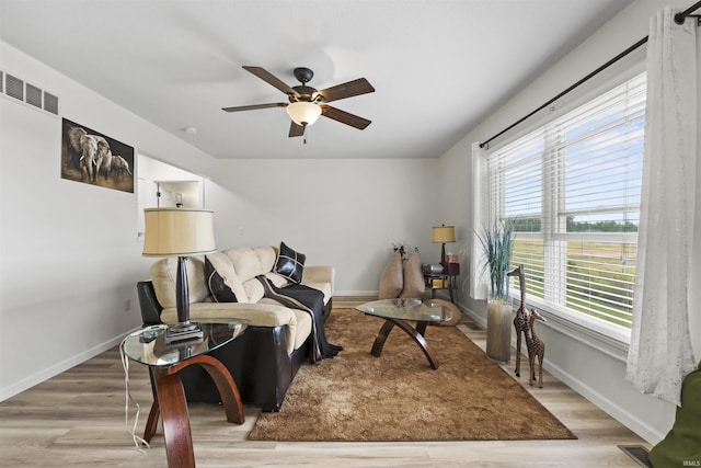 sitting room with a ceiling fan, wood finished floors, visible vents, and baseboards