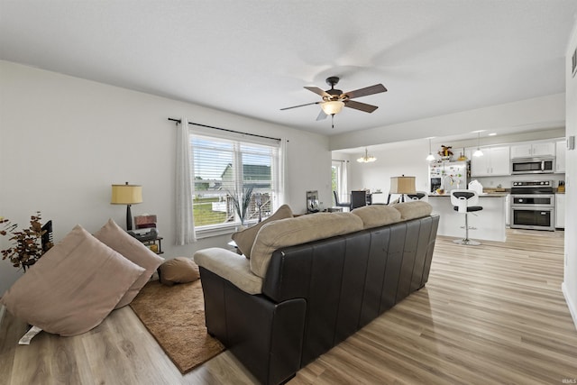 living room featuring light wood-type flooring and a ceiling fan