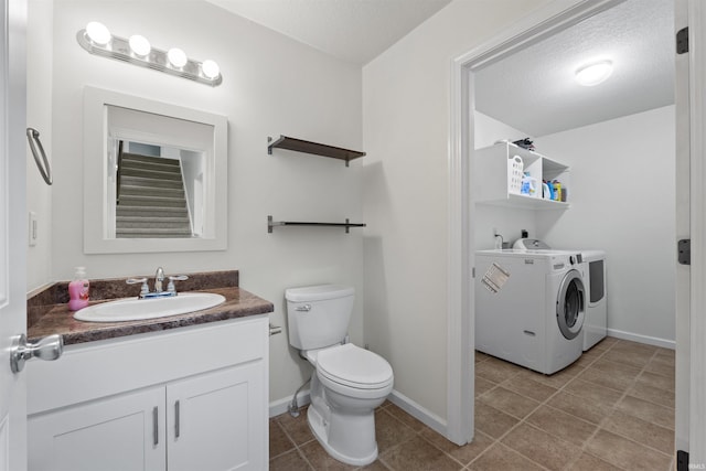 bathroom featuring baseboards, washing machine and dryer, toilet, tile patterned floors, and vanity