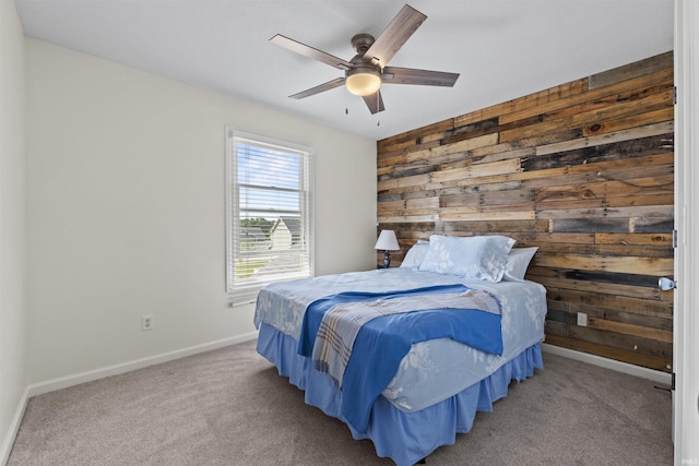 bedroom with baseboards, wood walls, carpet floors, and ceiling fan