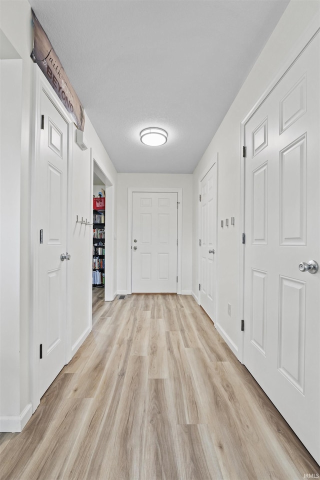 hall with baseboards and light wood-type flooring