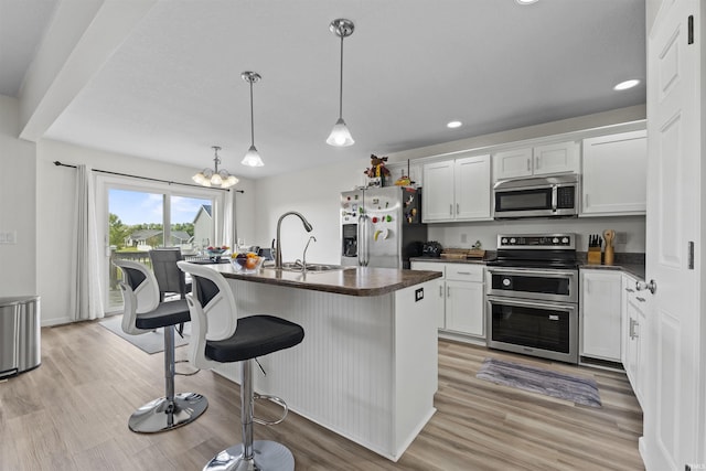 kitchen featuring a sink, dark countertops, light wood finished floors, and stainless steel appliances