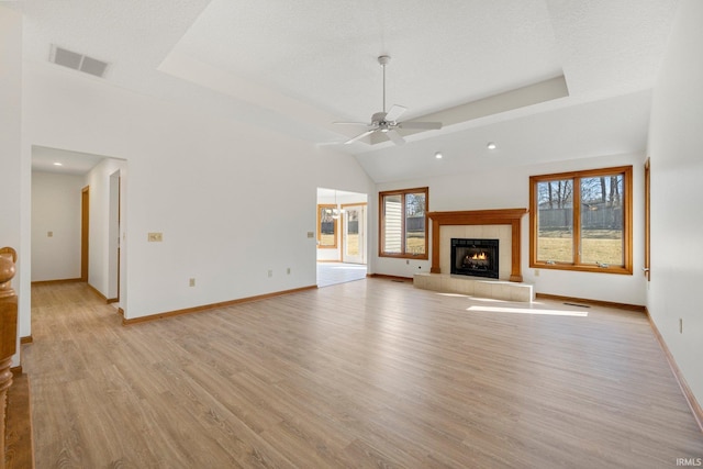 unfurnished living room featuring visible vents, a tiled fireplace, a ceiling fan, light wood-style floors, and baseboards