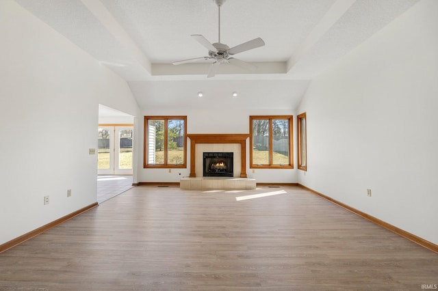 unfurnished living room featuring a fireplace, wood finished floors, baseboards, and ceiling fan