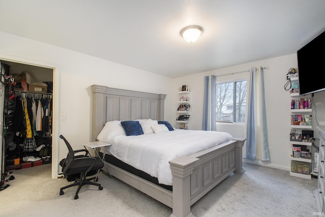 bedroom with a spacious closet, light colored carpet, and a closet