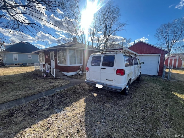 view of front of property featuring an outdoor structure, a garage, dirt driveway, and a front lawn