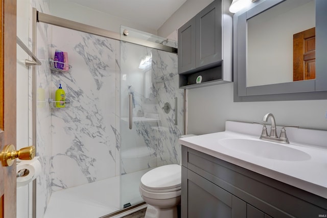 bathroom featuring a marble finish shower, toilet, and vanity