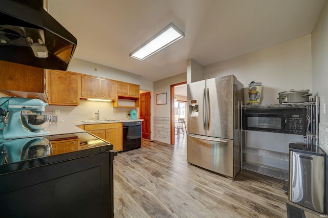 kitchen with visible vents, under cabinet range hood, light wood-type flooring, black appliances, and a sink