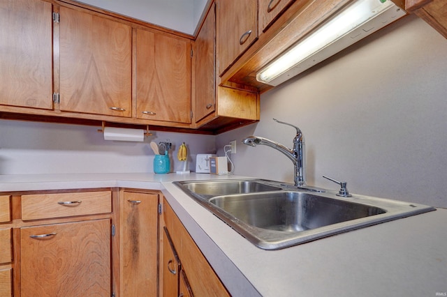 kitchen with light countertops, brown cabinetry, and a sink