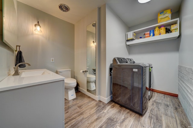 bathroom with washer and dryer, toilet, wood finished floors, and visible vents