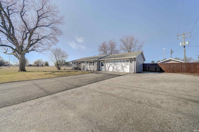 view of front of home featuring aphalt driveway, fence, a garage, and a front yard