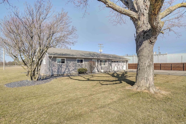 rear view of property with a yard, an attached garage, and fence