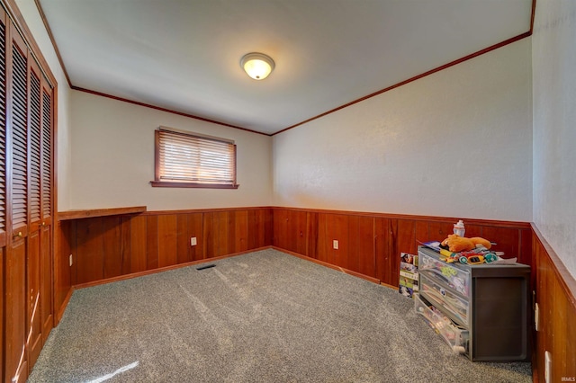 unfurnished bedroom with ornamental molding, visible vents, wood walls, and wainscoting