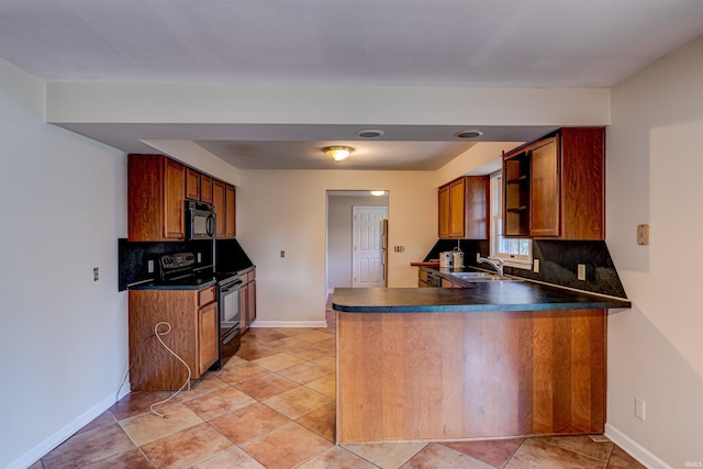 kitchen featuring decorative backsplash, brown cabinets, a peninsula, black appliances, and a sink