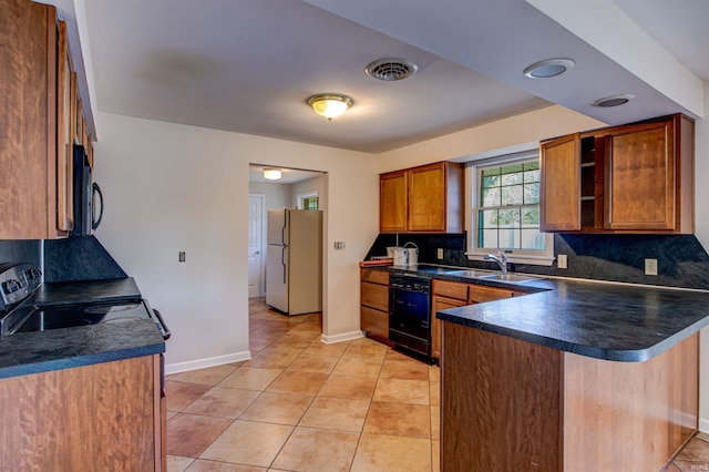 kitchen featuring dark countertops, tasteful backsplash, a peninsula, black appliances, and a sink