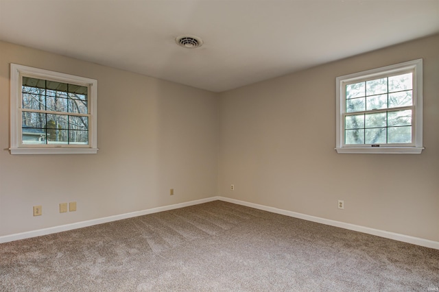 spare room featuring carpet, visible vents, and baseboards