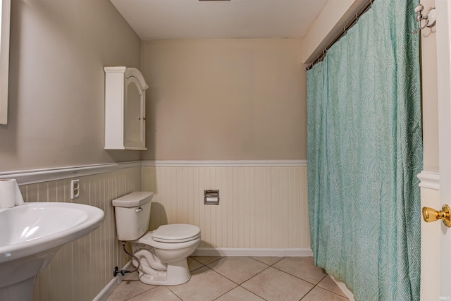 full bathroom featuring tile patterned floors, a wainscoted wall, toilet, and a sink