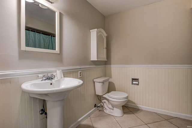 full bathroom featuring tile patterned floors, toilet, wainscoting, and a sink