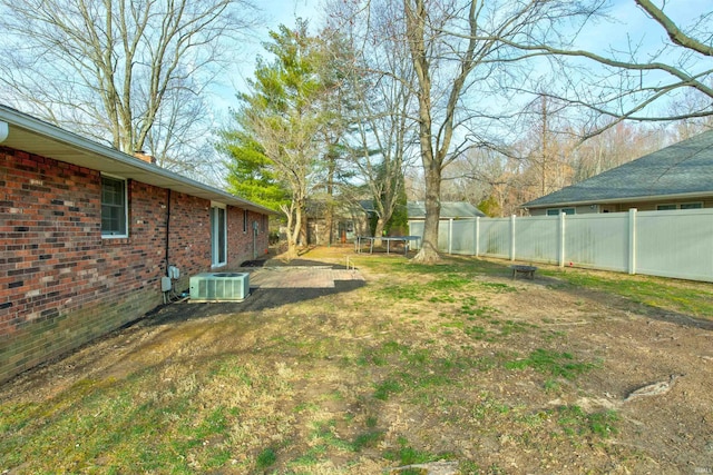 view of yard featuring central AC, a trampoline, and fence